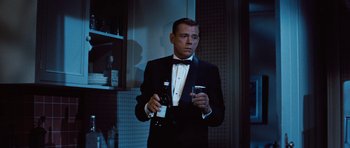 Movie still from “The Girl Can't Help It” (1956), directed by Frank Tashlin – A man in a tuxedo holding a bottle of alcohol and a cigarette; Medium shot, Low angle