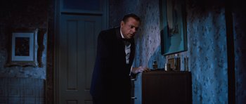 Movie still from “The Girl Can't Help It” (1956), directed by Frank Tashlin – A man in a suit and tie looking at something on a table; Medium shot, Low angle