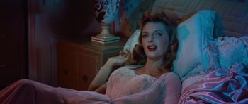 Movie still from “The Girl Can't Help It” (1956), directed by Frank Tashlin – A woman in a white dress laying in a bed; Medium shot, High angle