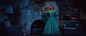 Movie still from “The Girl Can't Help It” (1956), directed by Frank Tashlin – A woman in a blue dress standing in front of a fireplace; Medium shot, Low angle