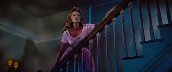 Movie still from “The Girl Can't Help It” (1956), directed by Frank Tashlin – A woman in a purple dress climbing a wooden stair railing; Medium shot, Low angle