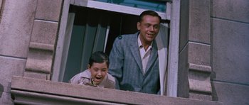 Movie still from “The Girl Can't Help It” (1956), directed by Frank Tashlin – A man standing next to a young boy in front of a window; Medium shot, Low angle