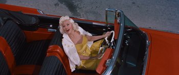 Movie still from “The Girl Can't Help It” (1956), directed by Frank Tashlin – A woman sitting in the driver's seat of an old car; Medium shot, Overhead angle