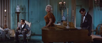 Movie still from “The Girl Can't Help It” (1956), directed by Frank Tashlin – A woman sitting on top of a wooden piano; Medium shot, High angle