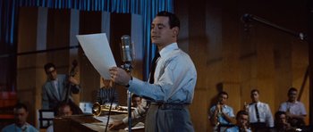 Movie still from “The Girl Can't Help It” (1956), directed by Frank Tashlin – A man holding a sheet of paper while standing in front of a microphone; Medium shot, Low angle