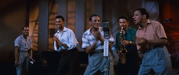 Movie still from “The Girl Can't Help It” (1956), directed by Frank Tashlin – A group of men standing next to each other on a stage; Medium shot, High angle