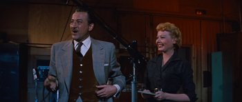 Movie still from “The Girl Can't Help It” (1956), directed by Frank Tashlin – An older man standing next to an older woman in front of a microphone; Medium shot, Over the shoulder angle