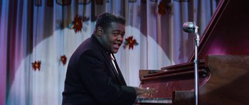 Movie still from “The Girl Can't Help It” (1956), directed by Frank Tashlin – A man in a black jacket playing a piano; Medium shot, High angle