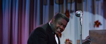 Movie still from “The Girl Can't Help It” (1956), directed by Frank Tashlin – A man in a black suit smiling for the camera; Close Up shot, Low angle