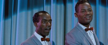 Movie still from “The Girl Can't Help It” (1956), directed by Frank Tashlin – A man in a suit and bow tie standing next to another man in a suit and bow tie standing next to another man; Close Up shot, Low angle