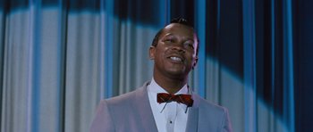 Movie still from “The Girl Can't Help It” (1956), directed by Frank Tashlin – A man in a suit and bow tie smiling; Close Up shot, Low angle