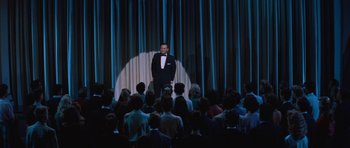 Movie still from “The Girl Can't Help It” (1956), directed by Frank Tashlin – A man standing on a stage in front of an audience; Wide shot, High angle