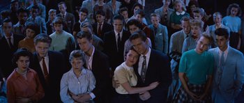 Movie still from “The Girl Can't Help It” (1956), directed by Frank Tashlin – A group of people standing together in a room; Medium shot, High angle