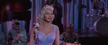 Movie still from “The Girl Can't Help It” (1956), directed by Frank Tashlin – A woman in a blue dress with pink flowers in her hair; Medium shot, Low angle