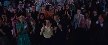 Movie still from “The Girl Can't Help It” (1956), directed by Frank Tashlin – A group of people standing in front of each other clapping; Medium shot, High angle
