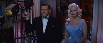 Movie still from “The Girl Can't Help It” (1956), directed by Frank Tashlin – A man in a tuxedo and a woman in a blue dress; Medium shot, Low angle