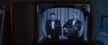 Movie still from “The Girl Can't Help It” (1956), directed by Frank Tashlin – Two men in tuxedos are playing a song on a television; Medium shot, High angle