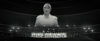 Movie still from “The Giver” (2014), directed by Phillip Noyce – A woman in a white dress is in front of an audience; Wide shot, Low angle