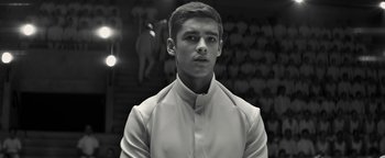 Movie still from “The Giver” (2014), directed by Phillip Noyce – A young man in a white shirt is standing in front of a crowd; Close Up shot, Low angle