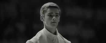 Movie still from “The Giver” (2014), directed by Phillip Noyce – A young man wearing a white shirt is looking at the camera; Close Up shot, Low angle