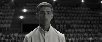 Movie still from “The Giver” (2014), directed by Phillip Noyce – A man in a white shirt is standing in front of a group of people; Close Up shot, Low angle