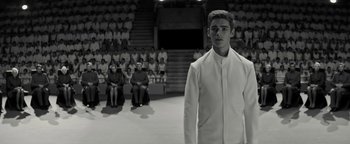 Movie still from “The Giver” (2014), directed by Phillip Noyce – A man in a white suit standing in front of a group of people; Medium shot, Low angle