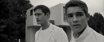 Movie still from “The Giver” (2014), directed by Phillip Noyce – Two young men standing next to each other in front of a building; Close Up shot, Low angle