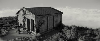Movie still from “The Giver” (2014), directed by Phillip Noyce – An old building on top of a hill with trees in the background; Extreme Wide shot, Low angle
