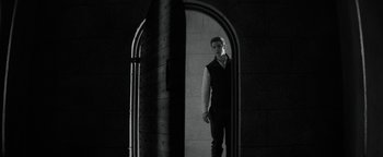 Movie still from “The Giver” (2014), directed by Phillip Noyce – A man standing in front of an arched mirror; Wide shot, Low angle