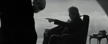 Movie still from “The Giver” (2014), directed by Phillip Noyce – A man sitting in a chair with a glass of wine; Medium shot, Over the shoulder angle