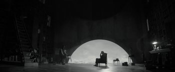 Movie still from “The Giver” (2014), directed by Phillip Noyce – A person sitting on a chair in a room; Extreme Wide shot, Over the shoulder angle