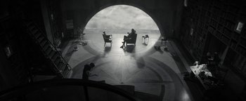 Movie still from “The Giver” (2014), directed by Phillip Noyce – Two people sitting in chairs in an open room; Extreme Wide shot, High angle