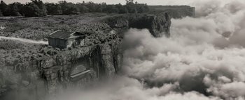 Movie still from “The Giver” (2014), directed by Phillip Noyce – A black and white photo of a cliff with a cloud coming out of it; Extreme Wide shot, High angle