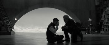 Movie still from “The Giver” (2014), directed by Phillip Noyce – Two men sitting on the ground one of them is holding his hand up to his ear; Wide shot, Low angle