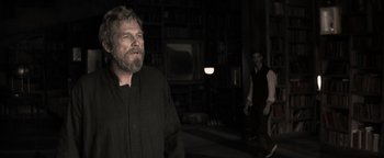 Movie still from “The Giver” (2014), directed by Phillip Noyce – A man standing in a dark room next to another man; Medium shot, Over the shoulder angle