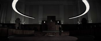 Movie still from “The Giver” (2014), directed by Phillip Noyce – A man sitting in front of an empty courtroom; Extreme Wide shot, Low angle