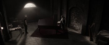 Movie still from “The Giver” (2014), directed by Phillip Noyce – A man and a woman sitting in front of a grand piano; Extreme Wide shot, High angle