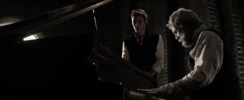 Movie still from “The Giver” (2014), directed by Phillip Noyce – A man standing in front of a grand piano; Medium shot, Over the shoulder angle
