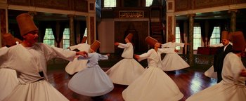 Movie still from “The Giver” (2014), directed by Phillip Noyce – A group of men in white dresses dancing in a room; Wide shot, High angle