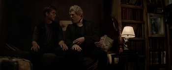 Movie still from “The Giver” (2014), directed by Phillip Noyce – Two men sitting on a couch talking to each other; Medium shot, Over the shoulder angle