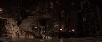Movie still from “The Giver” (2014), directed by Phillip Noyce – A man standing in front of a library full of books; Wide shot, High angle