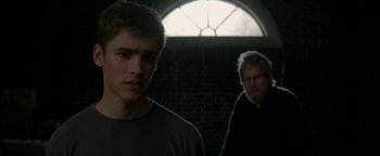 Movie still from “The Giver” (2014), directed by Phillip Noyce – Two men standing next to each other in front of a brick wall; Close Up shot, Over the shoulder angle