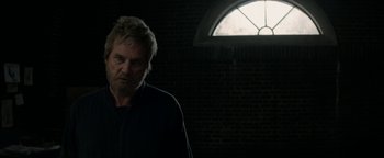 Movie still from “The Giver” (2014), directed by Phillip Noyce – A man standing in front of a window in a dark room; Close Up shot, Over the shoulder angle