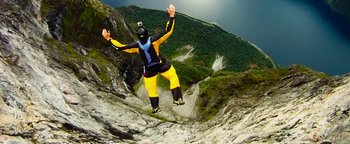 Movie still from “The Giver” (2014), directed by Phillip Noyce – A man in yellow and black is jumping off a cliff; Extreme Wide shot, Overhead angle