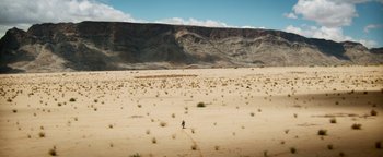 Movie still from “The Giver” (2014), directed by Phillip Noyce – A person riding a motorcycle in the middle of the desert; Extreme Wide shot, High angle