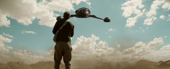 Movie still from “The Giver” (2014), directed by Phillip Noyce – A man standing under a flying object in the sky; Wide shot, Low angle