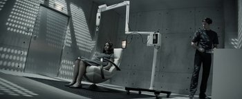 Movie still from “The Giver” (2014), directed by Phillip Noyce – A woman sitting in a chair in a room; Wide shot, High angle