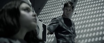 Movie still from “The Giver” (2014), directed by Phillip Noyce – A man with headphones standing in front of a wall; Close Up shot, Over the shoulder angle