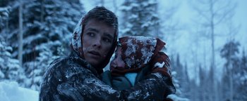 Movie still from “The Giver” (2014), directed by Phillip Noyce – A young man holding a young child in a snowy forest; Close Up shot, Over the shoulder angle