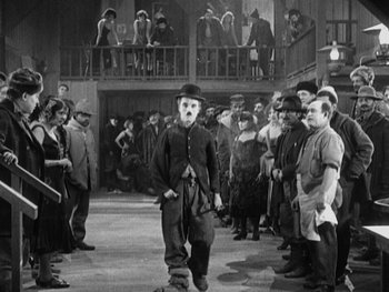 Movie still from “The Gold Rush” (1925), directed by Charles Chaplin – A group of people standing in front of a building; Wide shot, Low angle